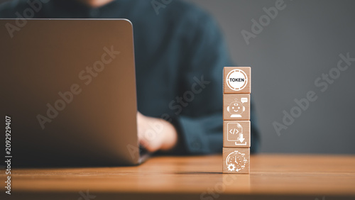 AI language model token usage and chatbot automation cost concept. Wooden cube tower with token chatbot coding and time icons in front of person working on laptop.