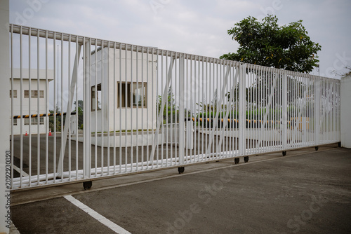 White sliding gate guarding the entrance of a commercial facility or industrial building with a security post.