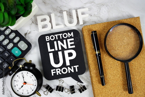 Foto BLUF - Bottom Line Up Front acronym with calculator, alarm clock and magnifying
