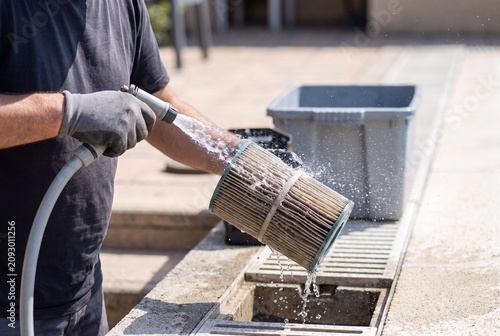 Spraying water on pleated pool filter cartridge