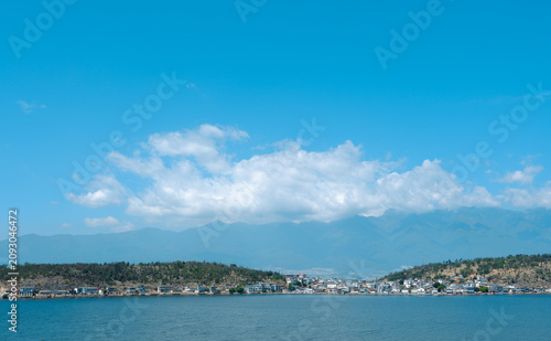 Calm lakeside town with mountains and blue sky