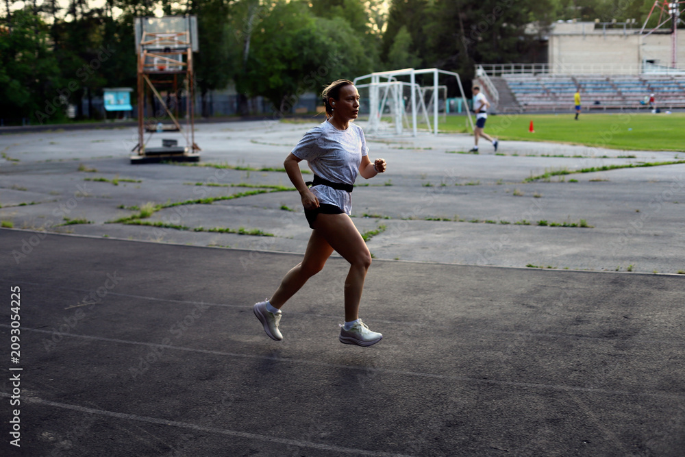 Obraz premium Adult European Woman Running in Open Stadium.