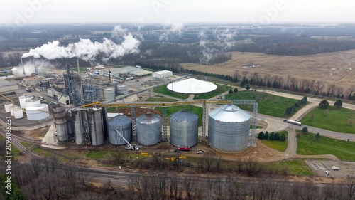 Aerial view of ethanol industrial plant with silos and smokestacks emitting steam.
