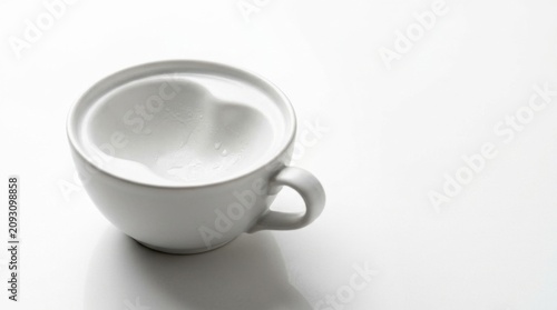 Side view angle of a clean round white porcelain coffee mug on a plain white background