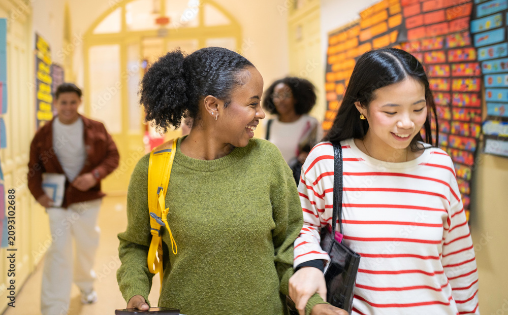 Obraz premium Diverse students walking together in university corridor, enjoying friendship and education