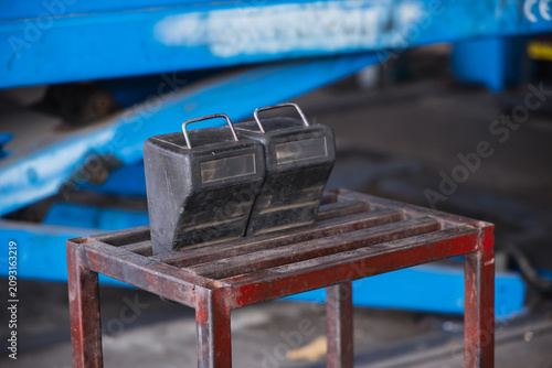 Fotografie Heavy-duty black rubber wheel chocks resting on a metal stand in an auto repair garage