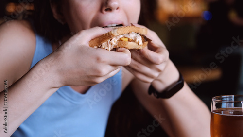 Bild auf Leinwand woman eating sandwich in dark setting with contentment close-up hand bread filling food lifestyle blue brown commercial natural light clean copy space editorial educational visual story web