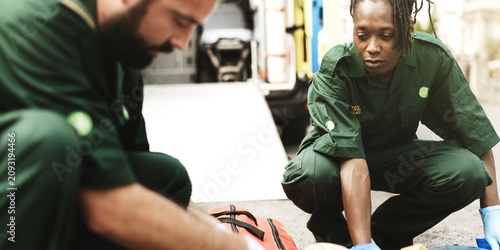 Bild auf Leinwand Paramedics in green uniforms attending to a patient outdoors.