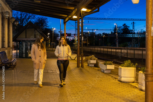 female friends walking on railway station platform at night