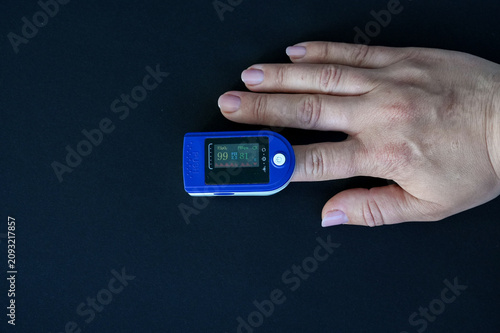 Foto Hand with pulse oximeter isolated on black background