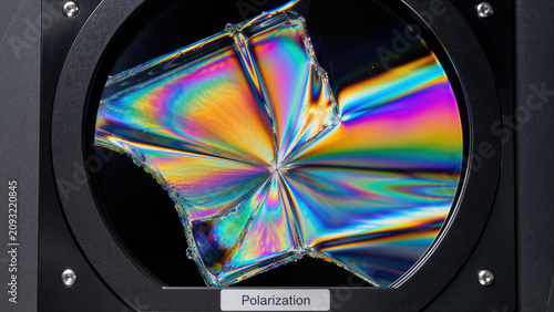 Light passes through a polarizer with a crystal exhibiting colorful patterns that illustrate the concept of polarization in a scientific setting