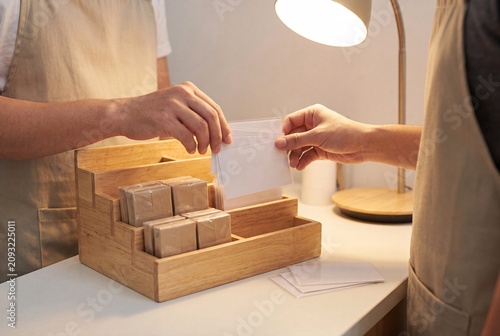 Retail Clerk Presenting Empty Business Cards To Client At Checkout Counter