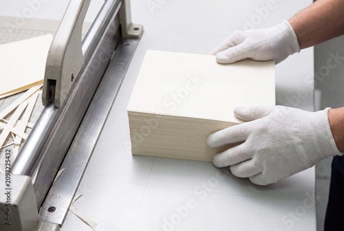 Print Shop Technician Using Industrial Guillotine To Trim Paper Stack