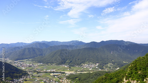 Konstfotografi Panoramic View of Lush Green Mountains Layered Under a Hazy Sky with a Distant R