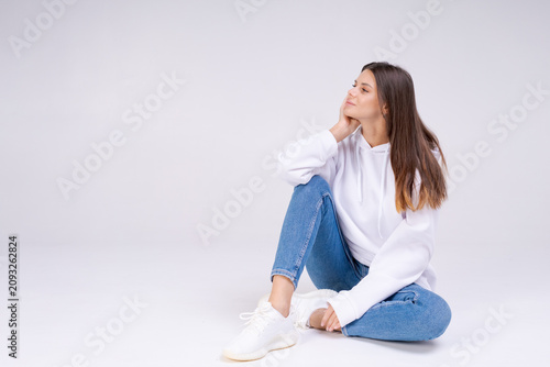 Obraz na płótnie Contemplative Caucasian Woman Looking Aside Sitting on Floor Dreamy Mood on Whit