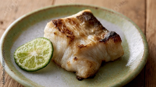 sudachi. A thin slice of green sudachi citrus beside grilled fish on a ceramic plate. menu design, packaging mockups, designed for culinary blogs and recipe cards for restaurants.