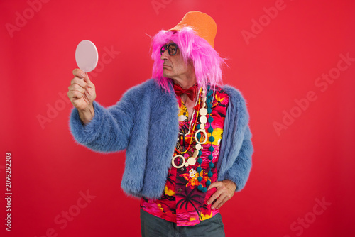 Принти на полотні Senior man in funky outfit and pink wig checking reflection in a mirror