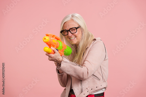 Принти на полотні Senior woman playing with water gun enjoying active maturity