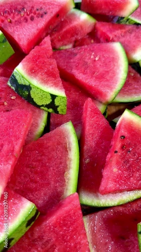 Vertical video social media - Closeup pan shot of water melon or watermelon, which has been cut into triangular slices, with thick green outer skin and juicy pink fruit, ready to eat.