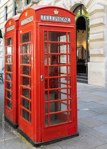 Two iconic British red telephone booths on a city sidewalk in London