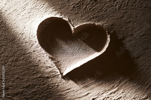 A heart-shaped indentation in textured earth, illuminated by a soft light