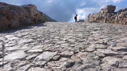 Hiker walking up an ancient cobblestone road in Mycenae