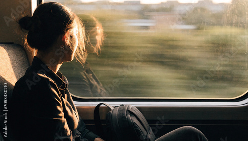 Young woman gazing out of a train window during a journey.