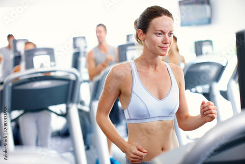 Fotografie Fitness, running and woman in center with treadmill, cardio exercise and calorie burn in speed workout