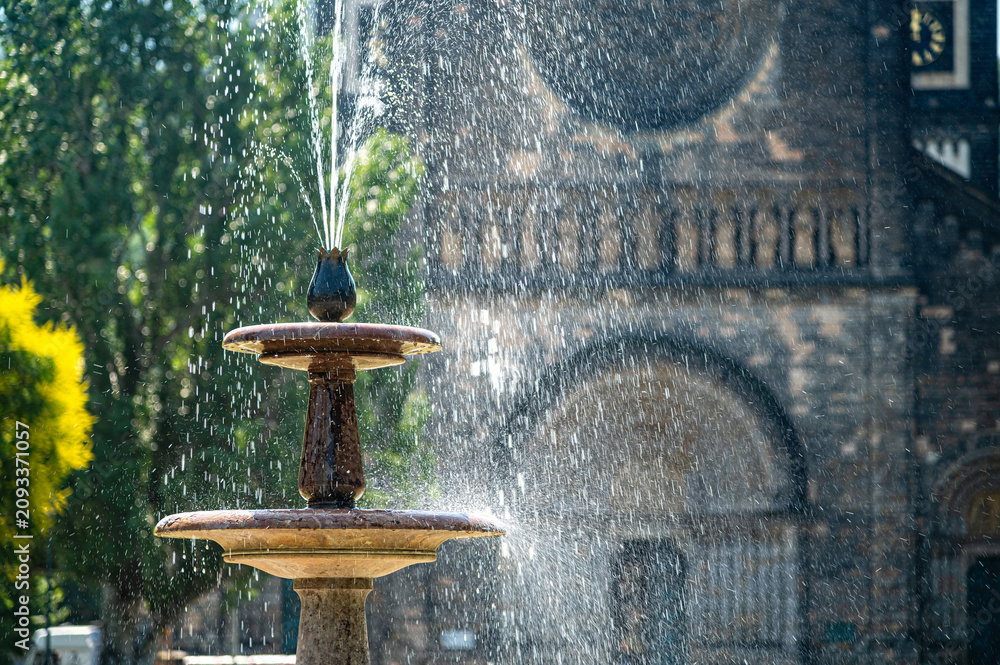 Obraz premium Fountain in Prague with water spraying near a historic building during daytime