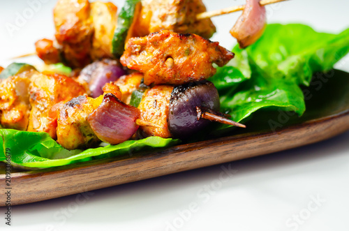 Grilled chicken and zucchini skewers rest on fresh lettuce