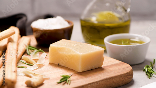 Photos Block of Parmesan cheese on a wooden board with breadsticks and olive oil