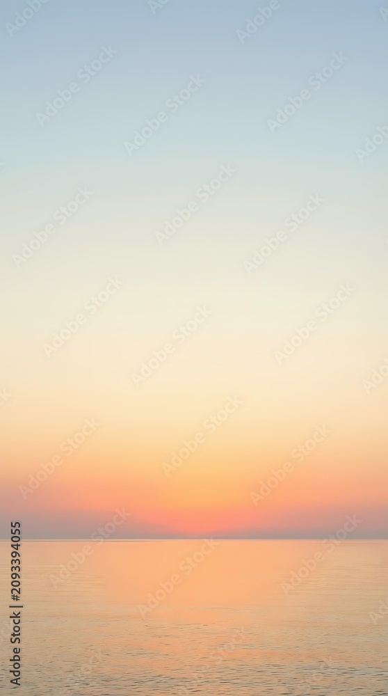 Obraz premium Serene ocean horizon at sunset with soft peachy and coral tones fading into pale blue sky, calm water surface reflecting warm light, tranquil seascape for relaxation and wellness projects.