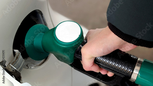 Bild auf Leinwand Refueling car at gas station, hand holding green fuel nozzle, filling petrol tan