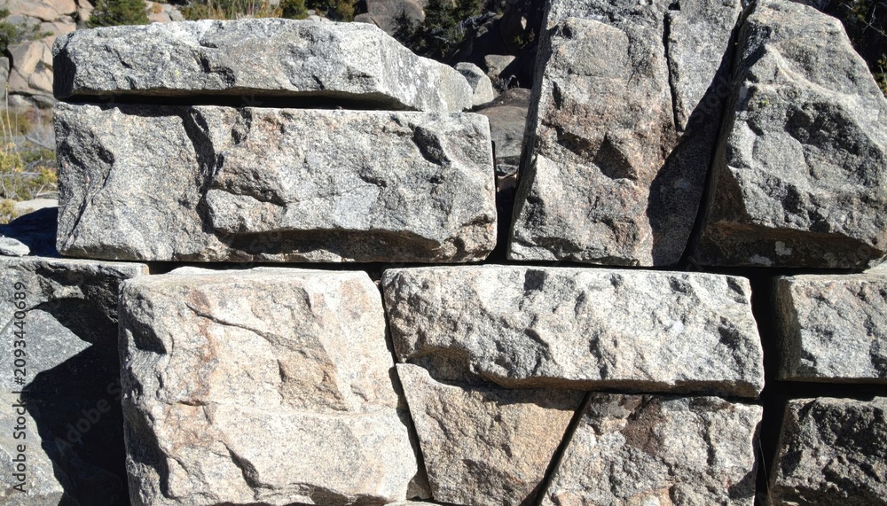 Fototapeta premium Stacked Natural Granite Stones Creating an Earthy Textured Wall Background