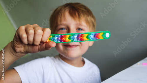 A boy holding a diamond mosaic bracelet craft close-up