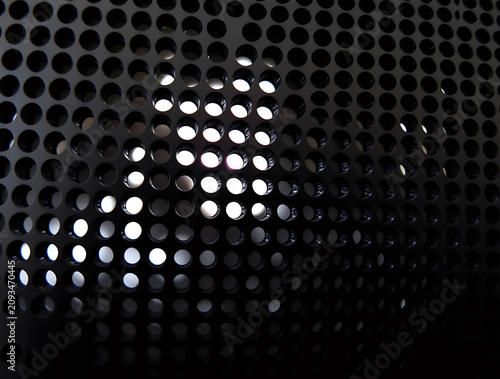Black Perforated Metal Grille with Bright Circular Lights Shining Through