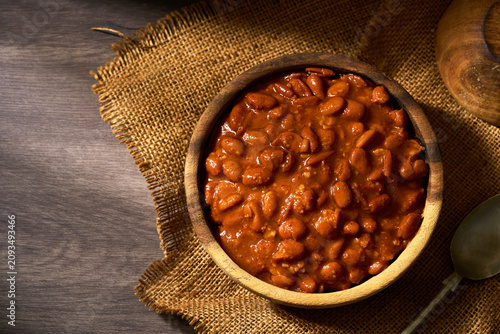 top view flat lay of delicious pinto bean stew, a classic cowboy meal in a rustic wooden bowl on a table background with copy space