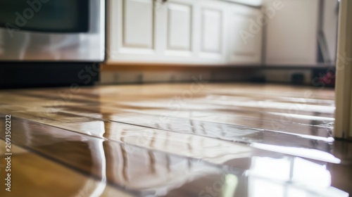 Water damage on a kitchen floor with water covering the wooden laminate parquet surface
