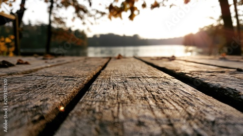 Golden hour sun shines on weathered wooden planks leading to tranquil lake