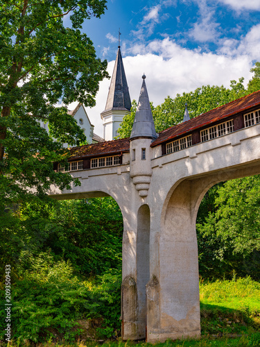 Konstfotografi 2025-09-01; Historic covered bridge with turrets against a spire in Ladek Zdroj Poland