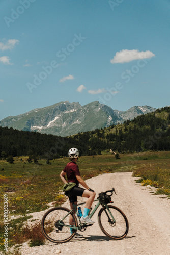 Photography Woman with a gravel bicycle admiring the mountains in Durmitor National Park, Montenegro