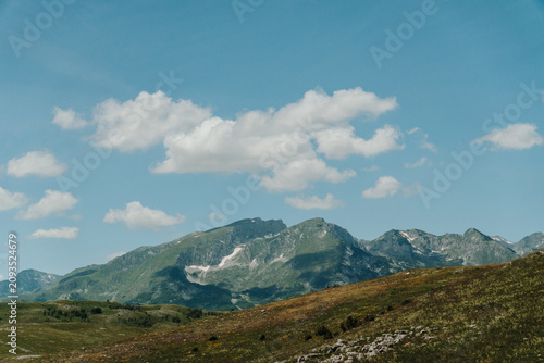 Fotografie Rocky mountain peaks rising above alpine meadows in Durmitor National Park, Montenegro
