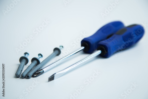 Close-up of two hands in work gloves holding screwdrivers against a white background. Concept of repair, handyman, tools, construction, installation. High quality photo