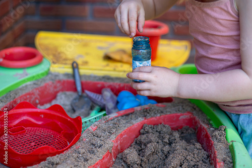 Canvastavla A child is playing with sand in the garden