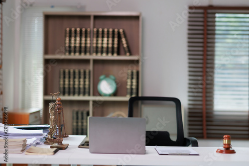 Lady Justice statue with laptop and legal documents on a lawyer's desk, representing law, justice, compliance, and legal services in a professional office setting