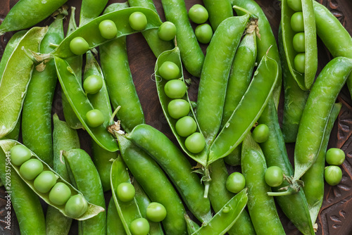 Fotografía Freshly harvested green pea pods filled with sweet peas, captured in a detailed close-up that celebrates seasonal farming and healthy eating