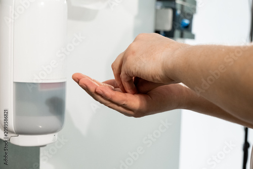 Φωτογραφία Man washes fingers with sanitizer from wall mounted dispenser unit closeup