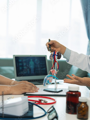 A urologist is explaining medication to a male patient with prostate or kidney issues and is handing a bottle of medicine to him.