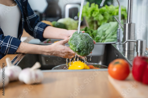Foto Close up of hands people washing vegetables by tap water at the sink in the kitchen to clean ingredient prepare a fresh salad