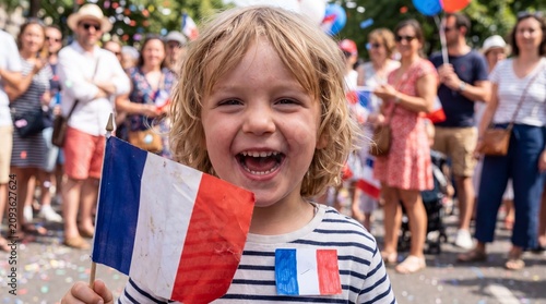 A French toddler wearing a paper badge laughs while holding a flag at a Bastille Day celebration for stock imagery